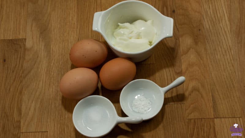 Foto van wolkenbrood recept ingrediënten op een houten ondergrond: yoghurt, eieren, bakpoeder en zout.